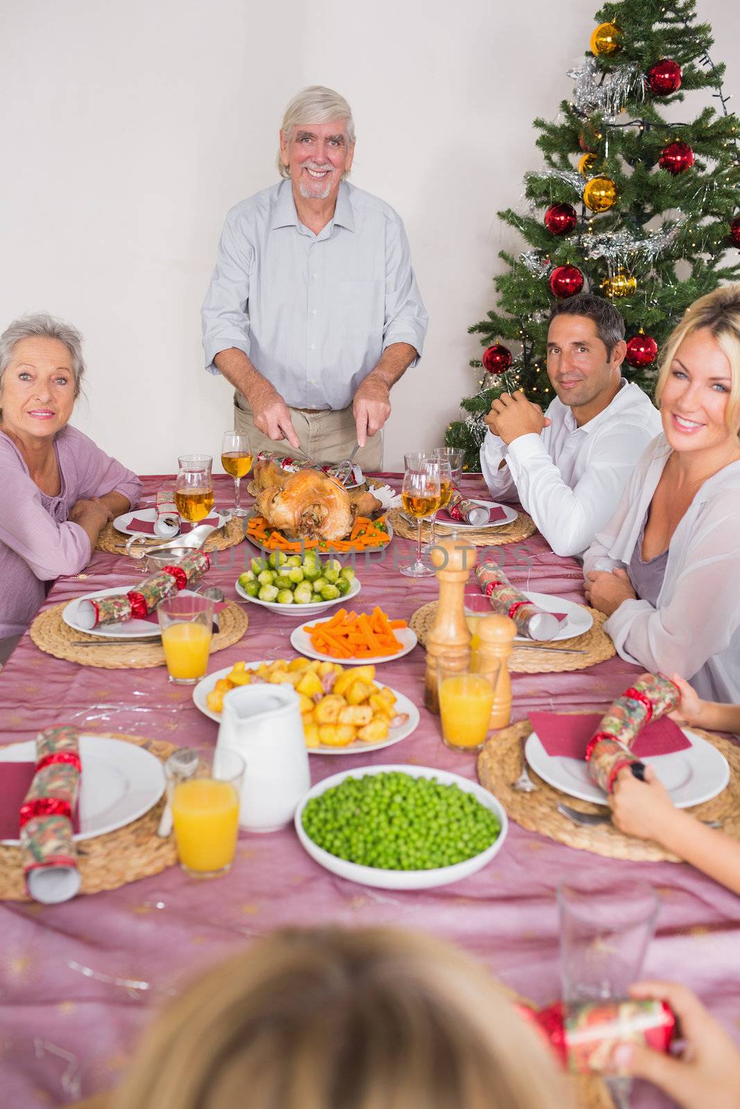 Happy grandfather carving the christmas turkey at the dinner table