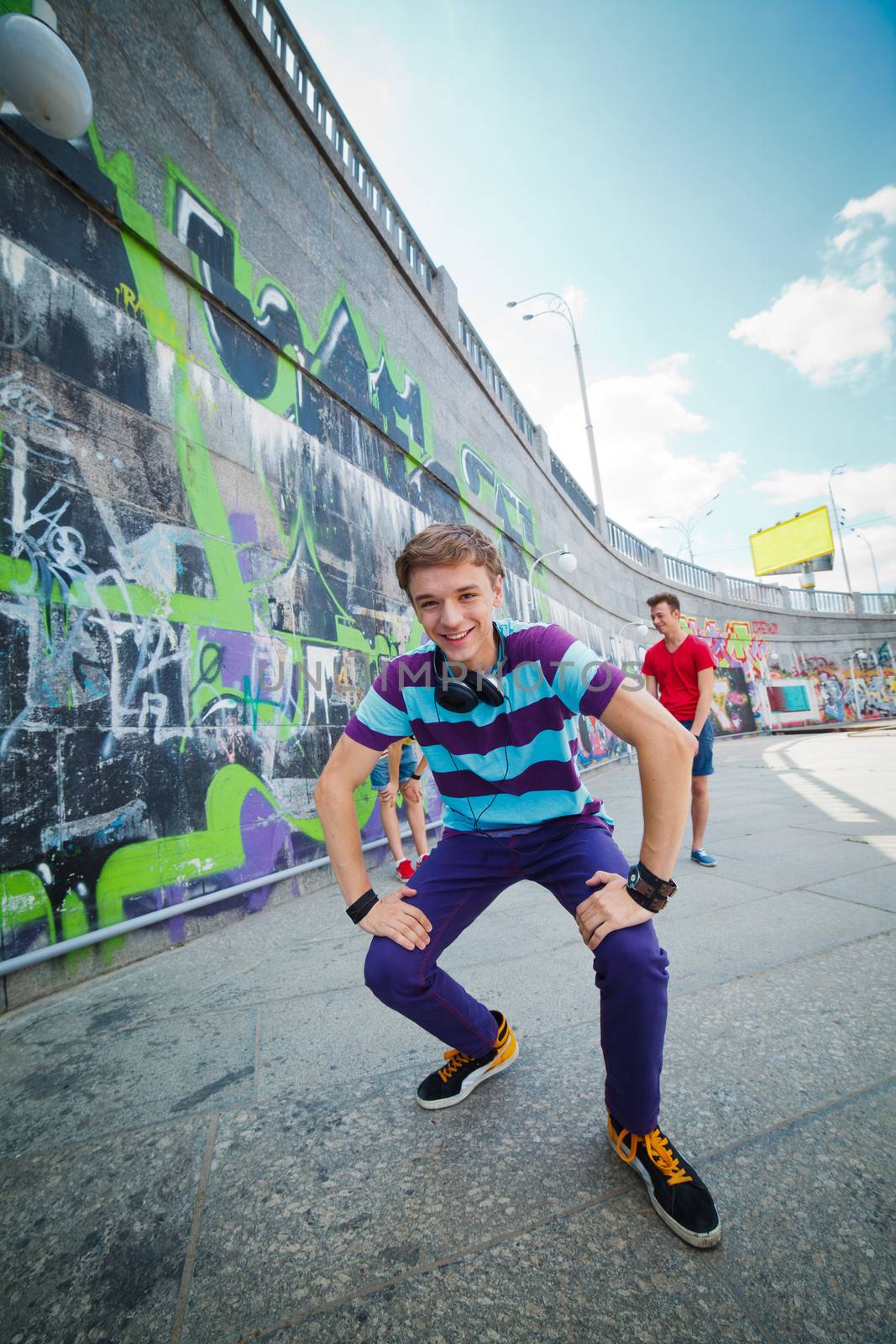 Happy teens boy with his friends by painted wall looking at camera. Vertical view