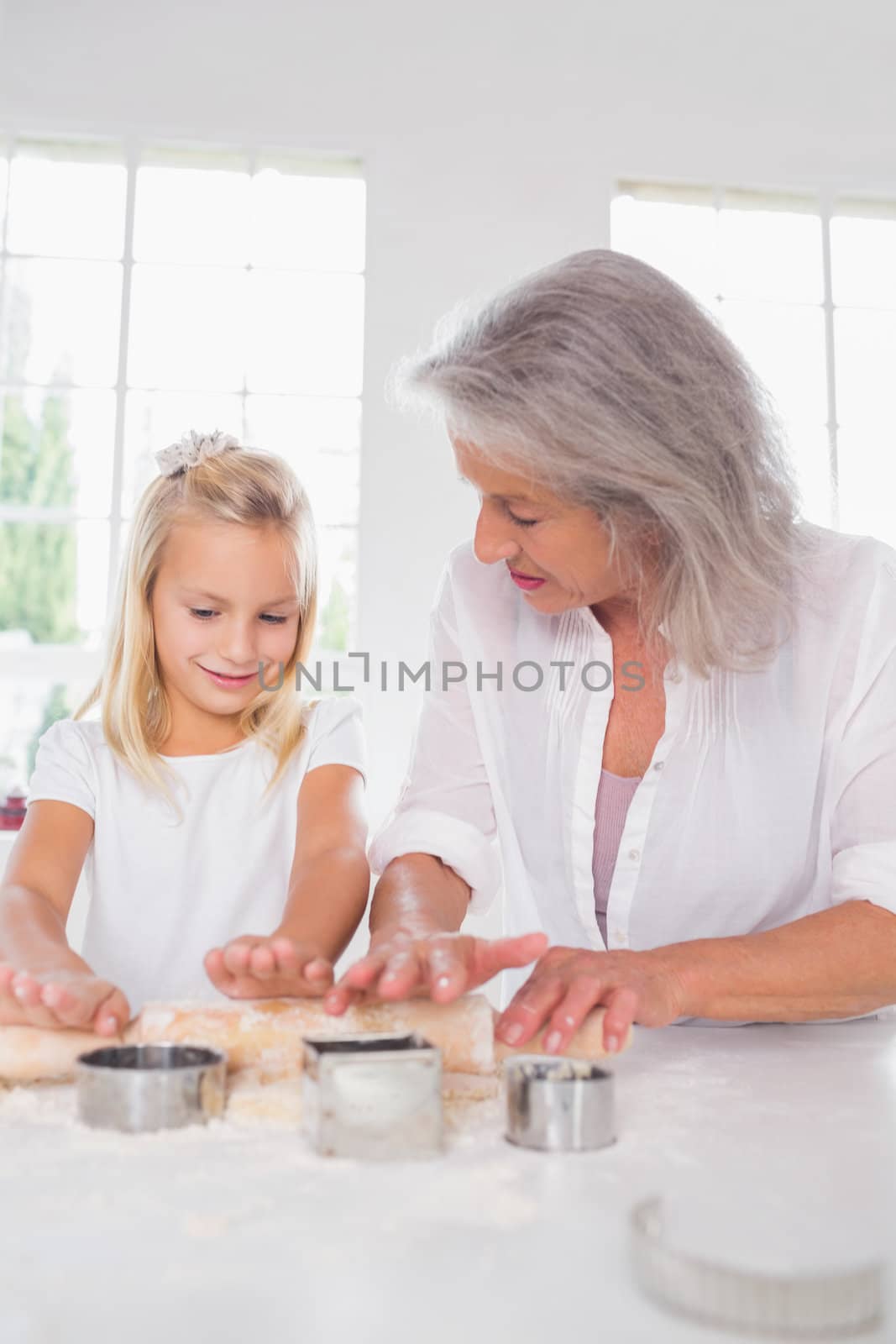 Granddaughter making biscuits with her grandmother in the kitchen