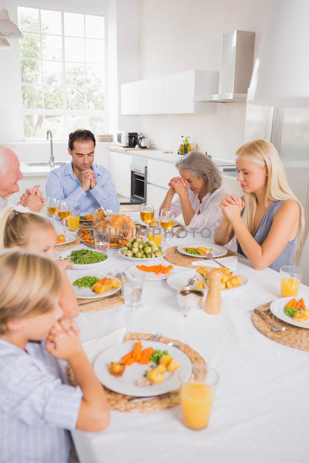 Family praying before eating by Wavebreakmedia