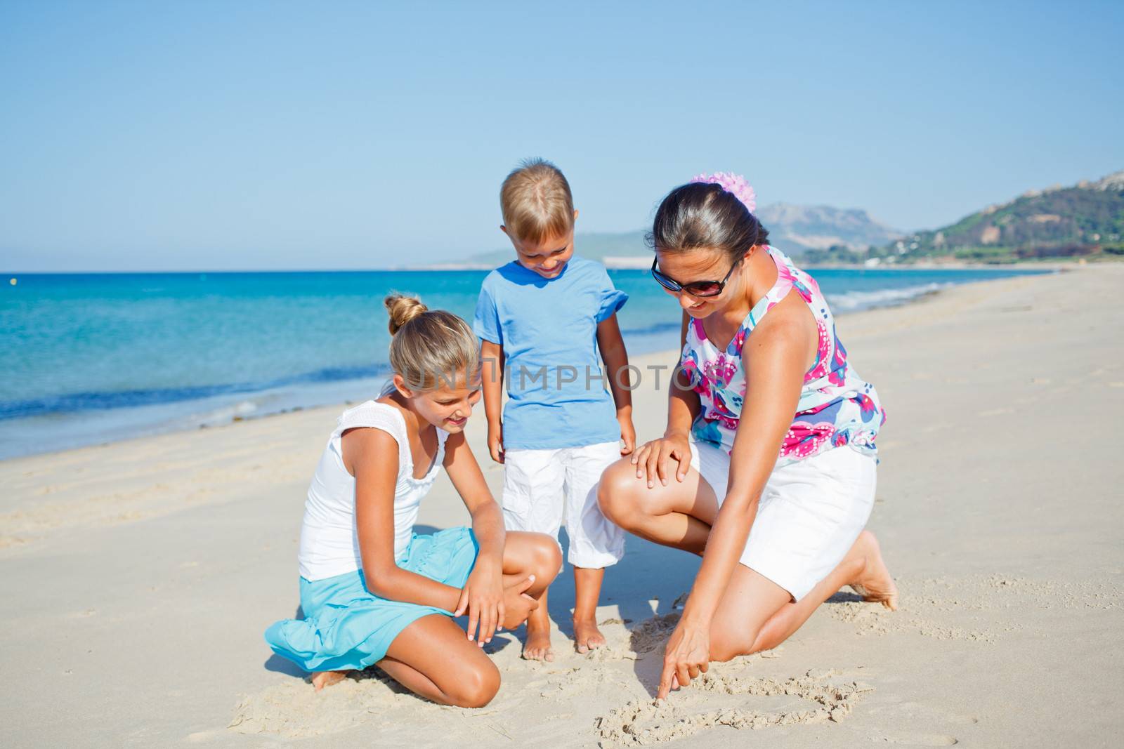 Adorable happy two kids with mother having fun on tropical beach