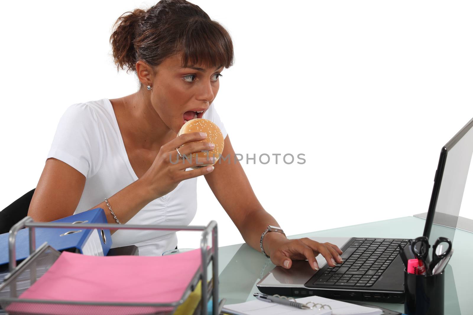 Woman eating a burger at her desk by phovoir