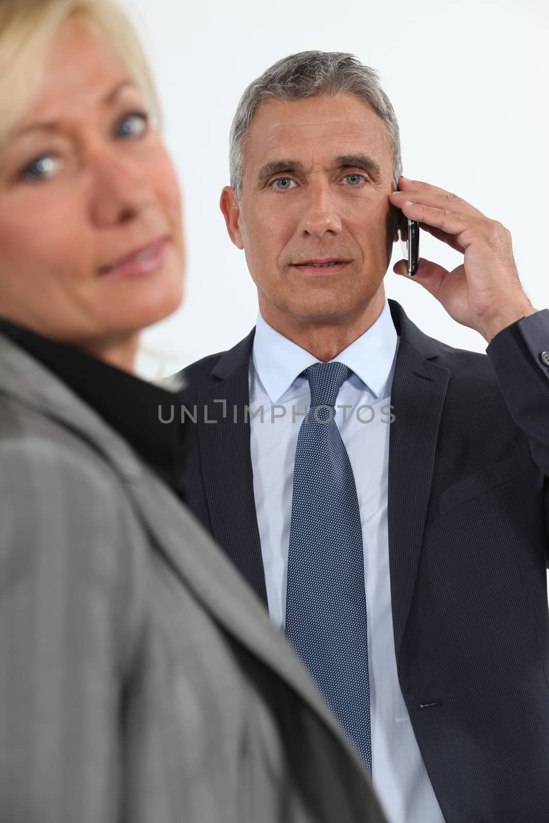Businessman talking on his mobile phone beside his colleague by phovoir