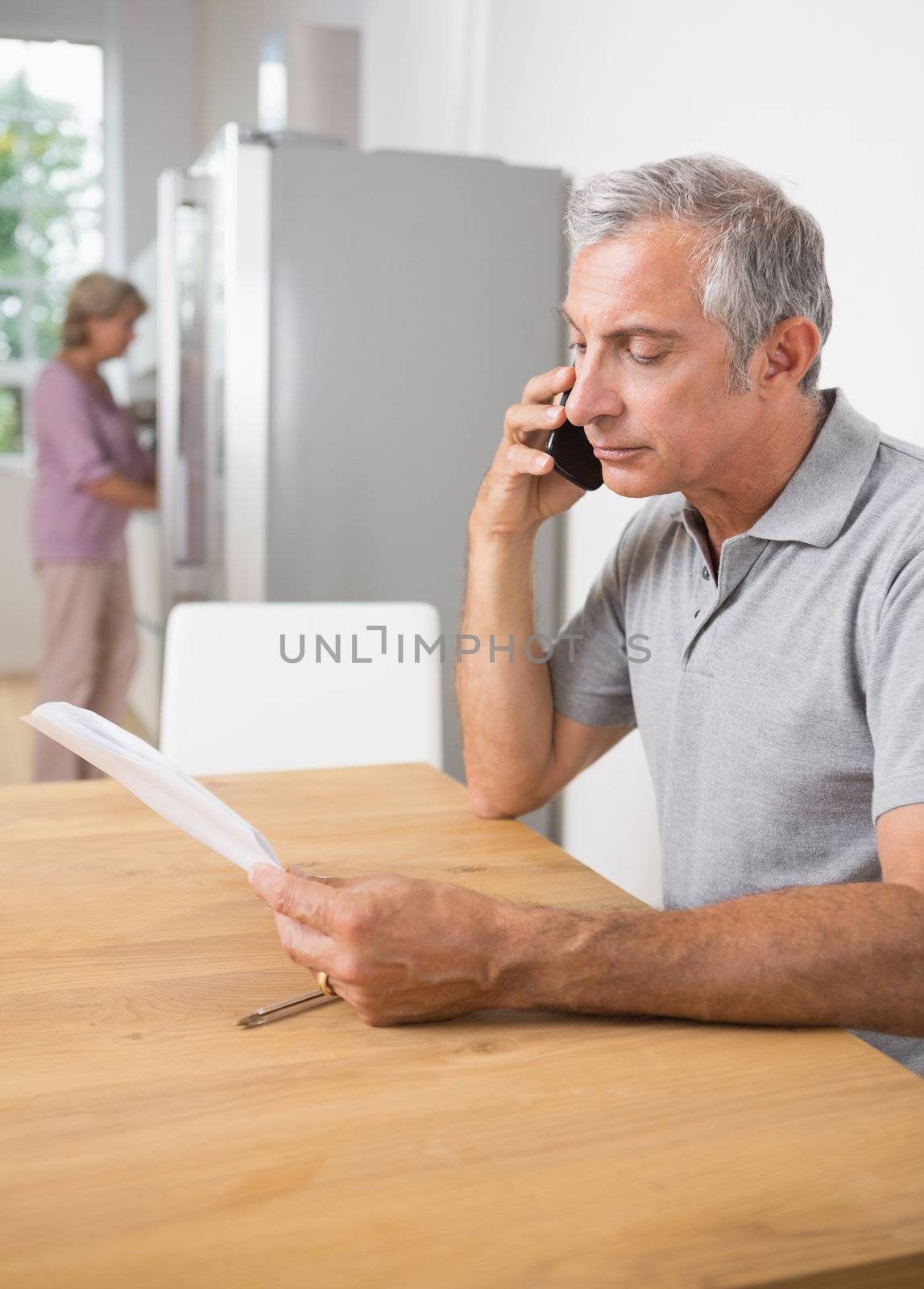 Mature man calling with a sheet of paper by Wavebreakmedia
