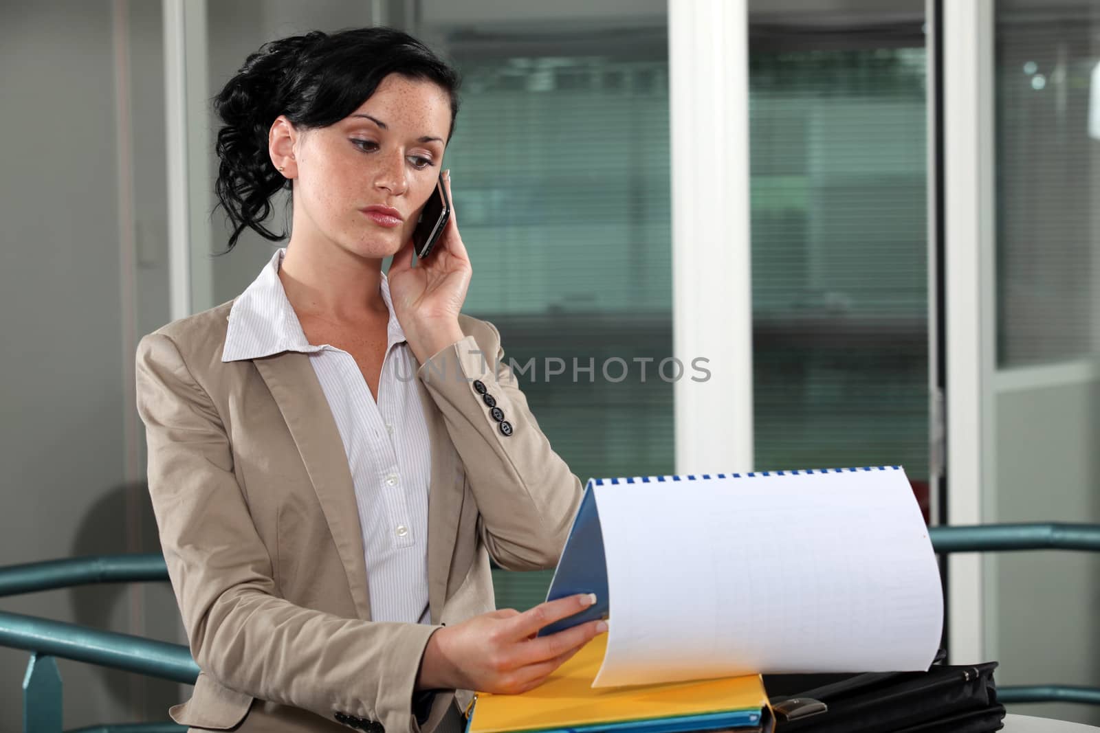 businesswoman talking on her cell and looking at her agenda by phovoir