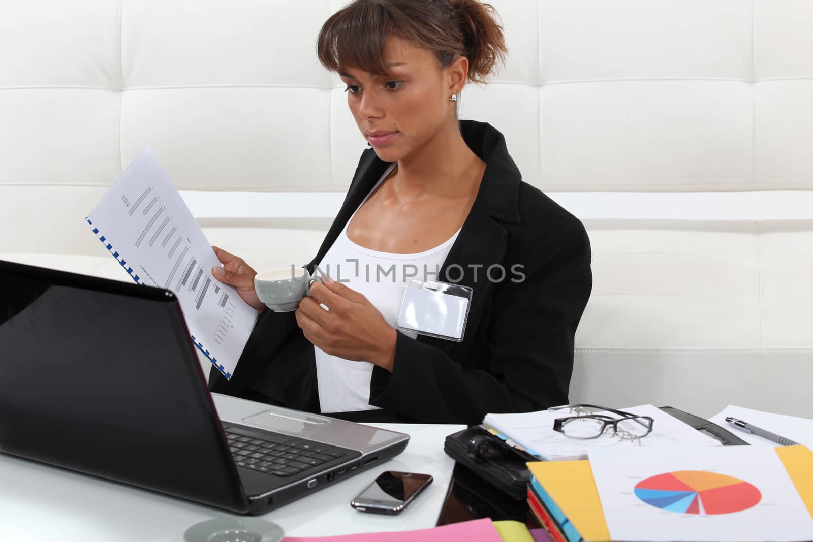 Businesswoman drinking coffee and looking at graphs by phovoir