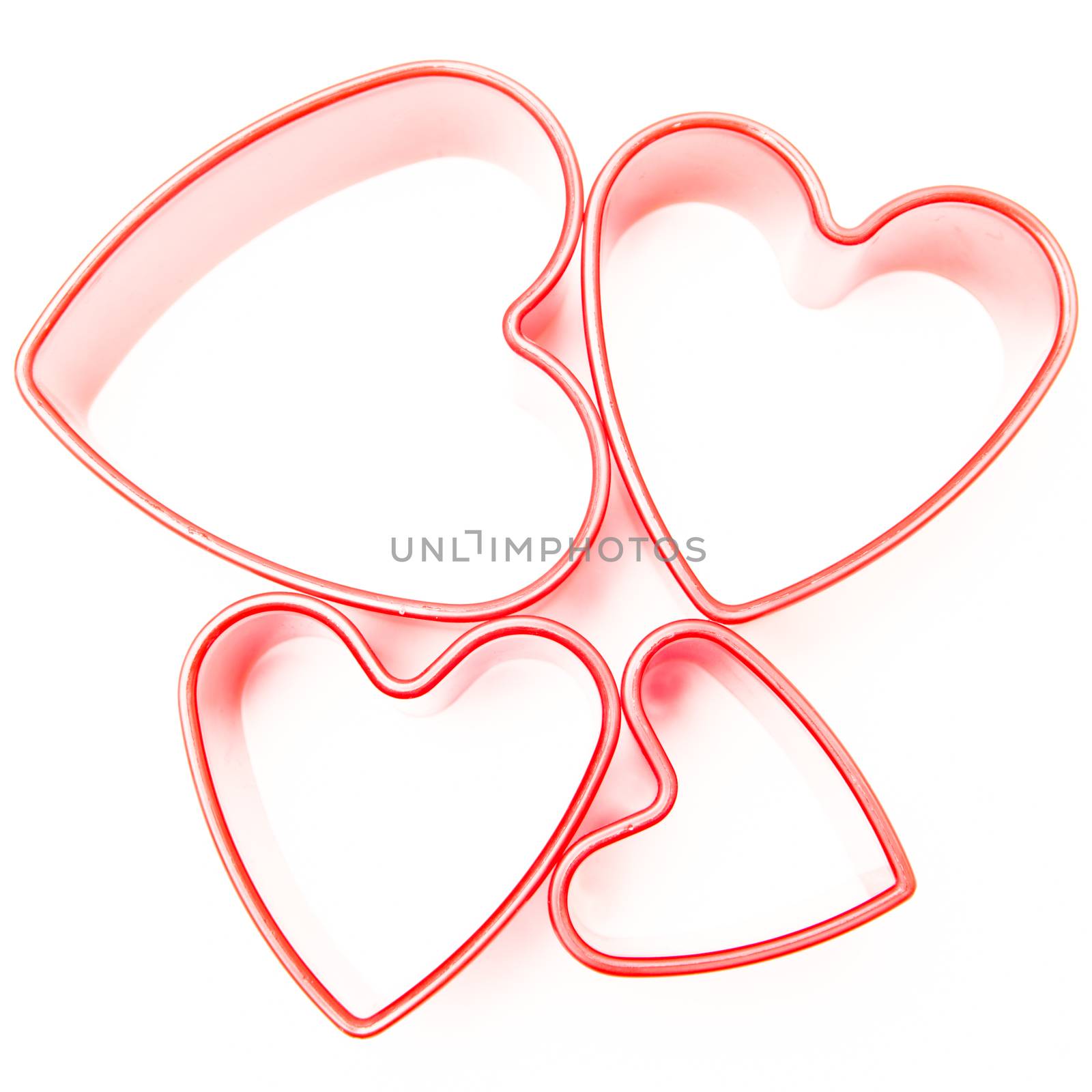 Four pink heart cookie cutters on white background