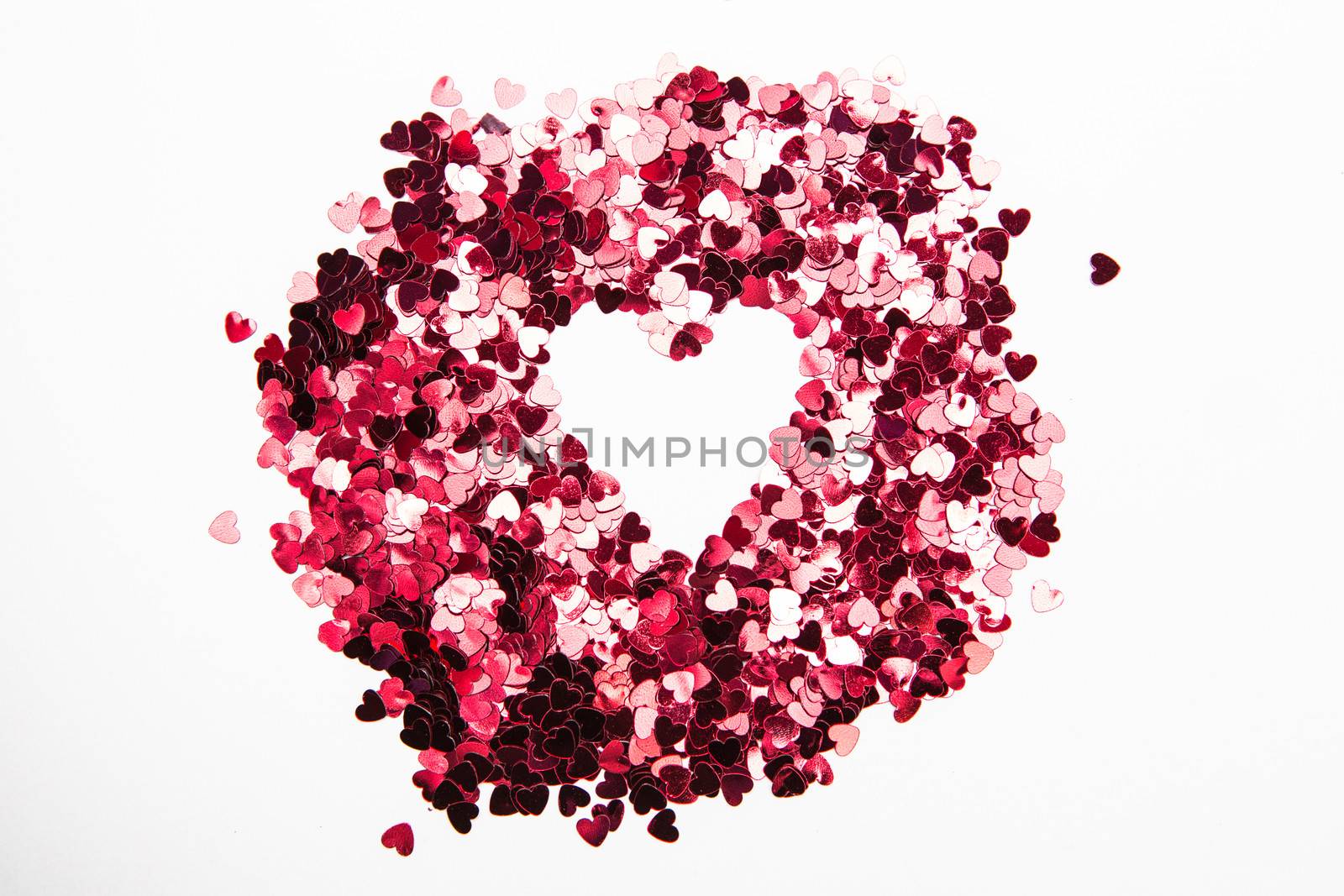 Pink heart confetti in inverted heart shape on white background