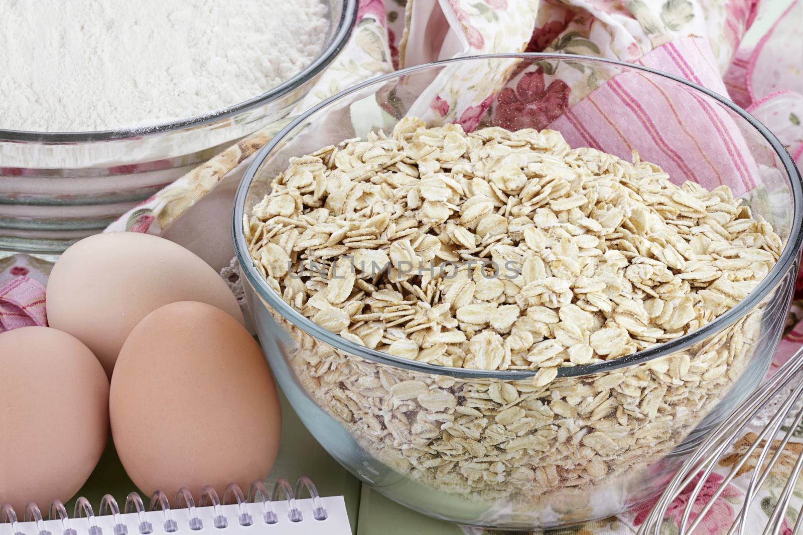 Bowl of whole grain oats with fresh eggs, flour and whisk. 
