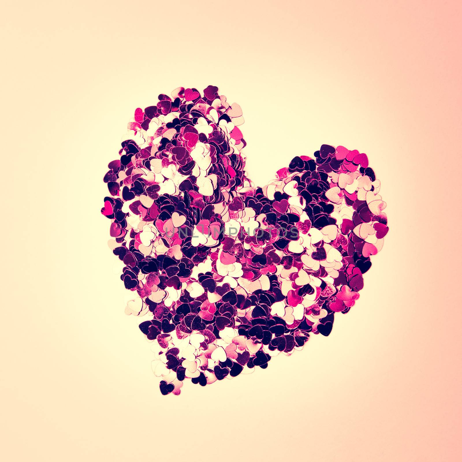 Pink confetti in heart shape on neutral background