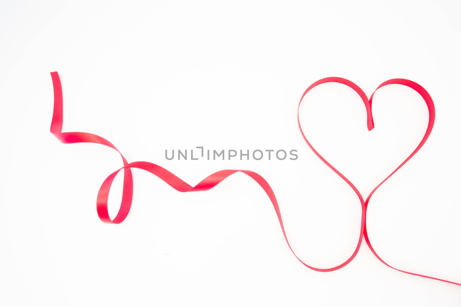 Decorative pink ribbon shaped into heart on white background