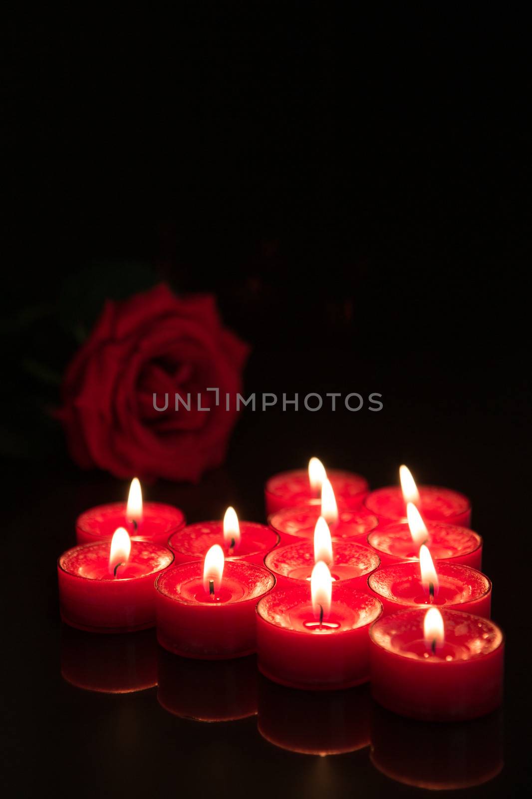 Romantic candles with red rose on black background