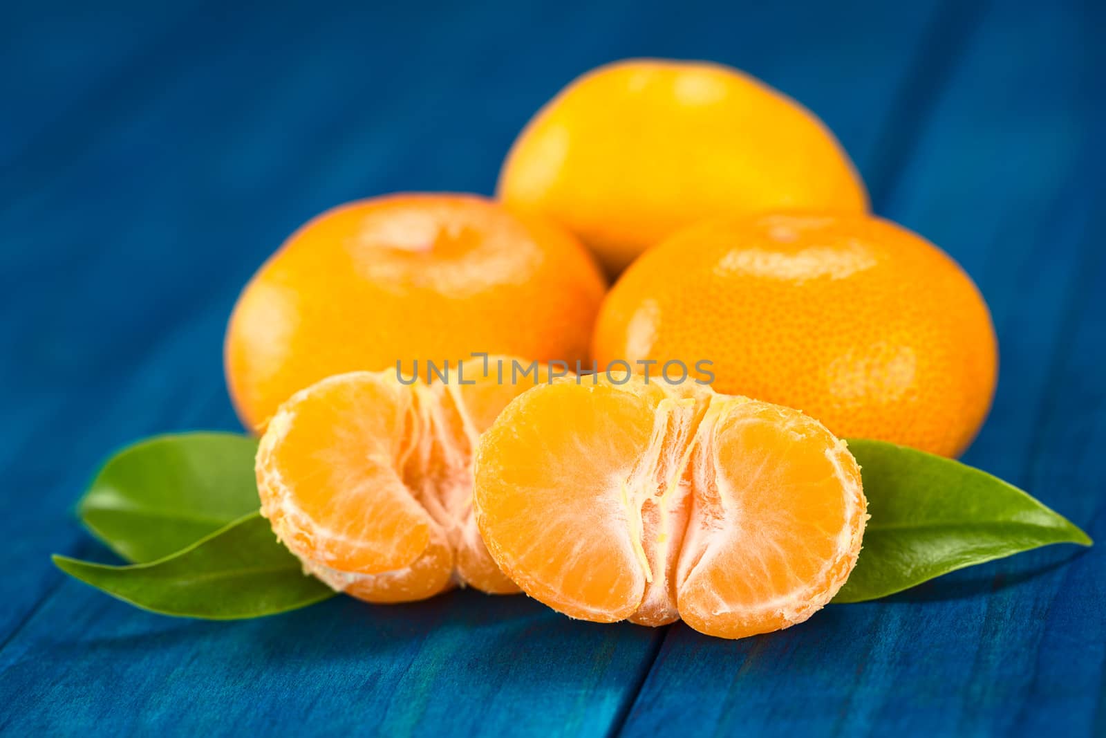 Mandarin halves with leaves on blue wood (Selective Focus, Focus on the front of the mandarin half) 