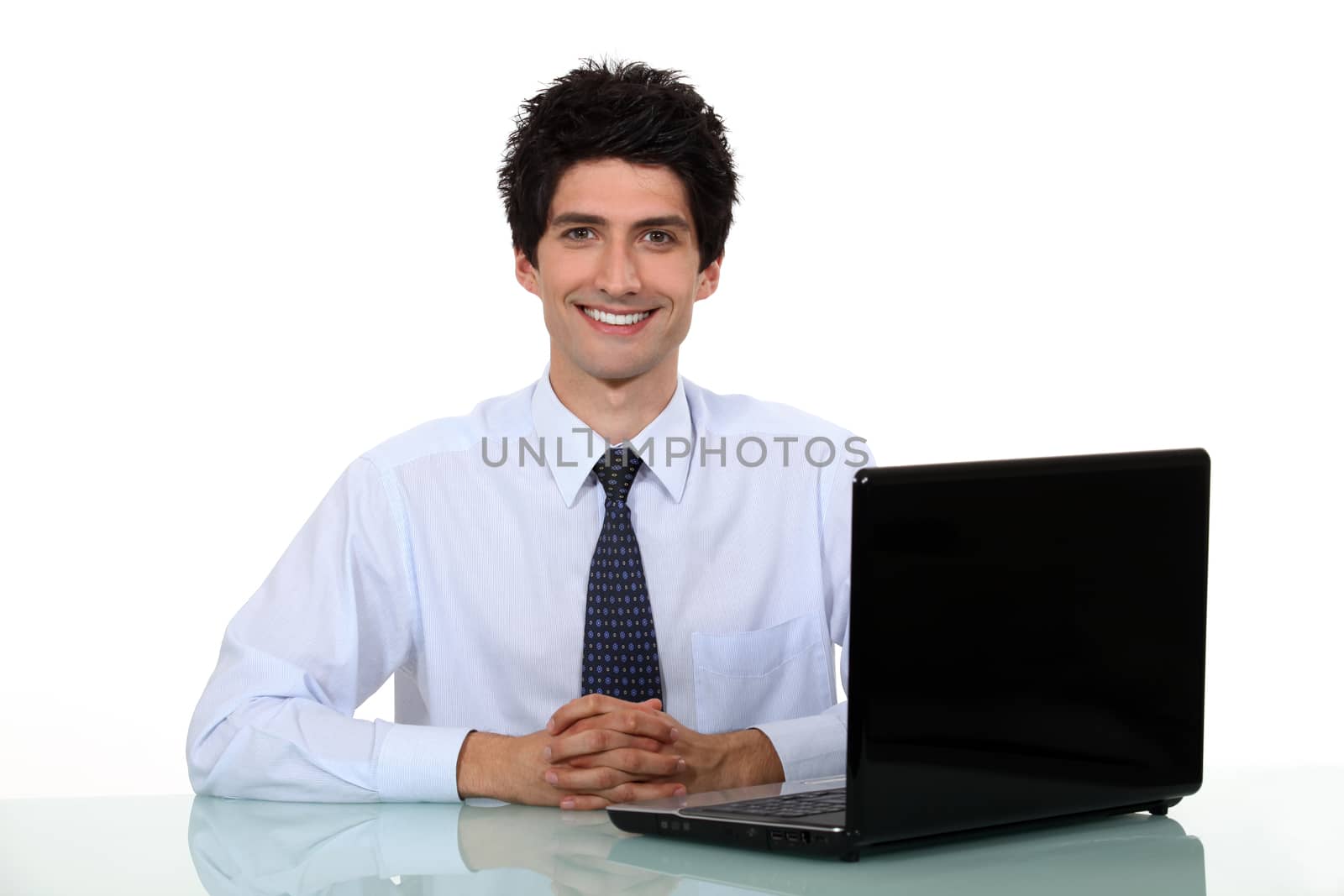 Happy office worker sat at his desk smiling by phovoir