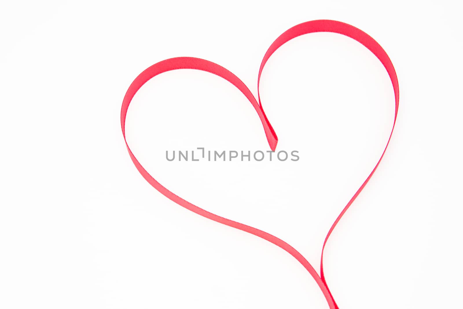 Pink heart shaped ribbon on white background