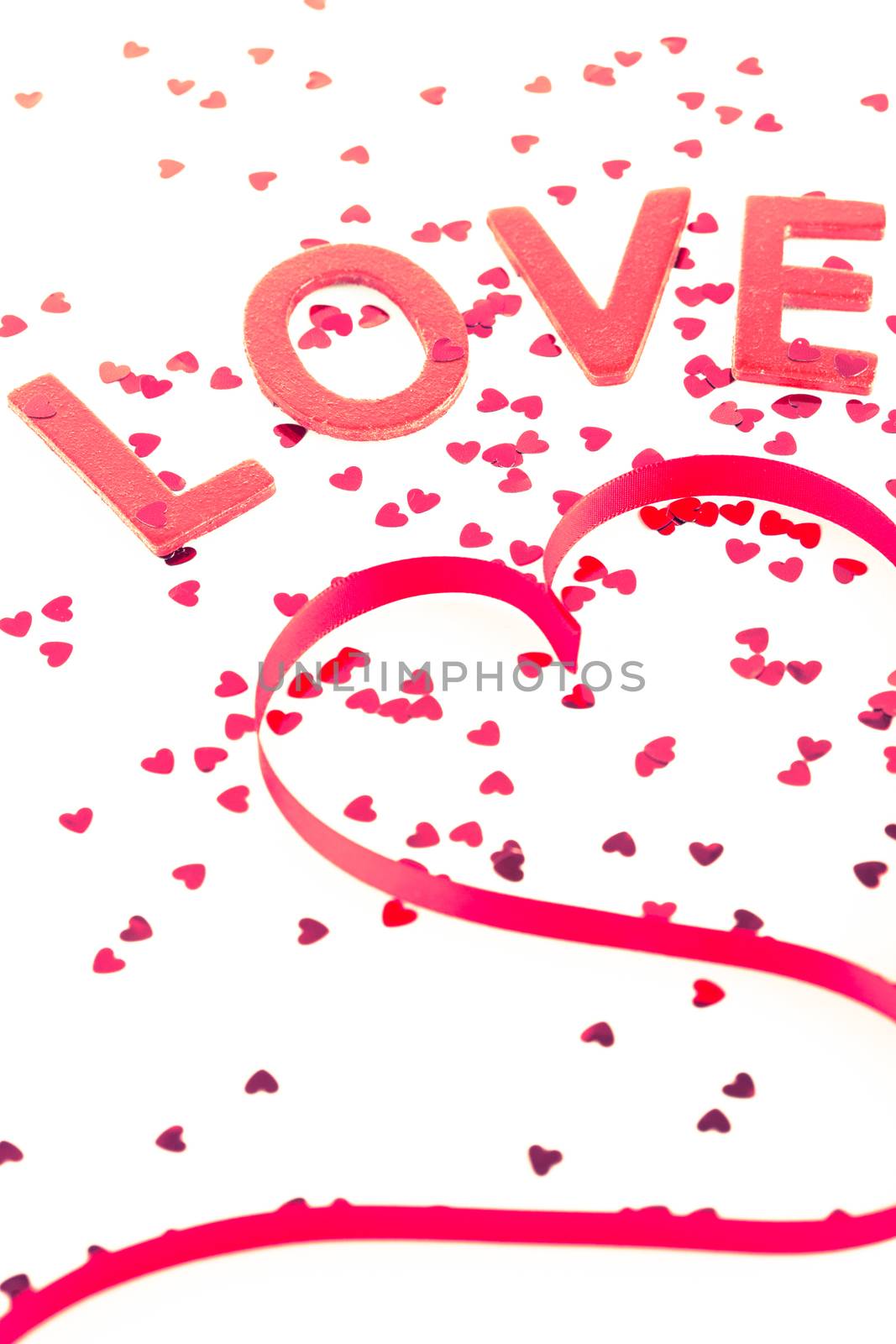 Love and heart shaped ribbon with pink confetti on white background