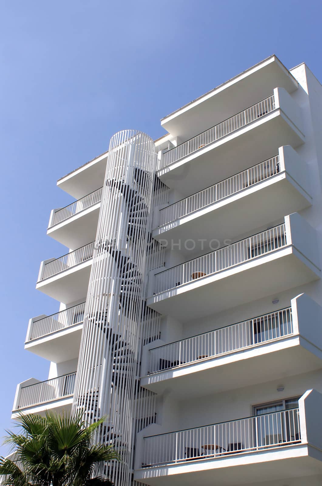 Low angle view of white tourist hotel with blue sky background.