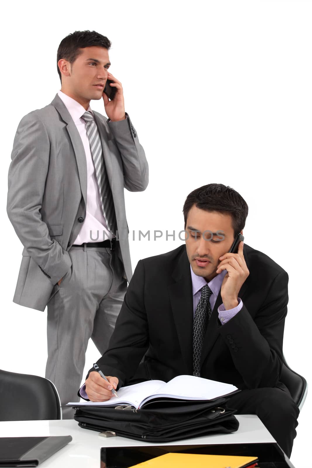Two businessmen working towards deadline by phovoir