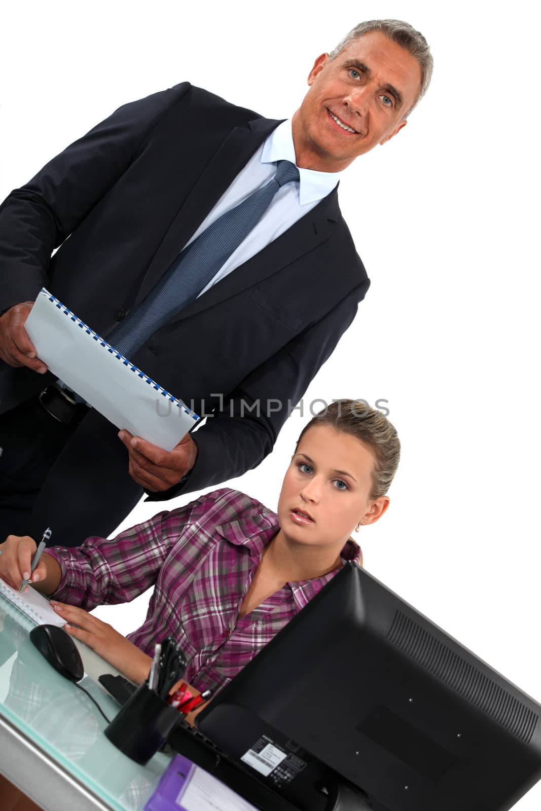 Smiling businessman standing over his overworked assistant by phovoir