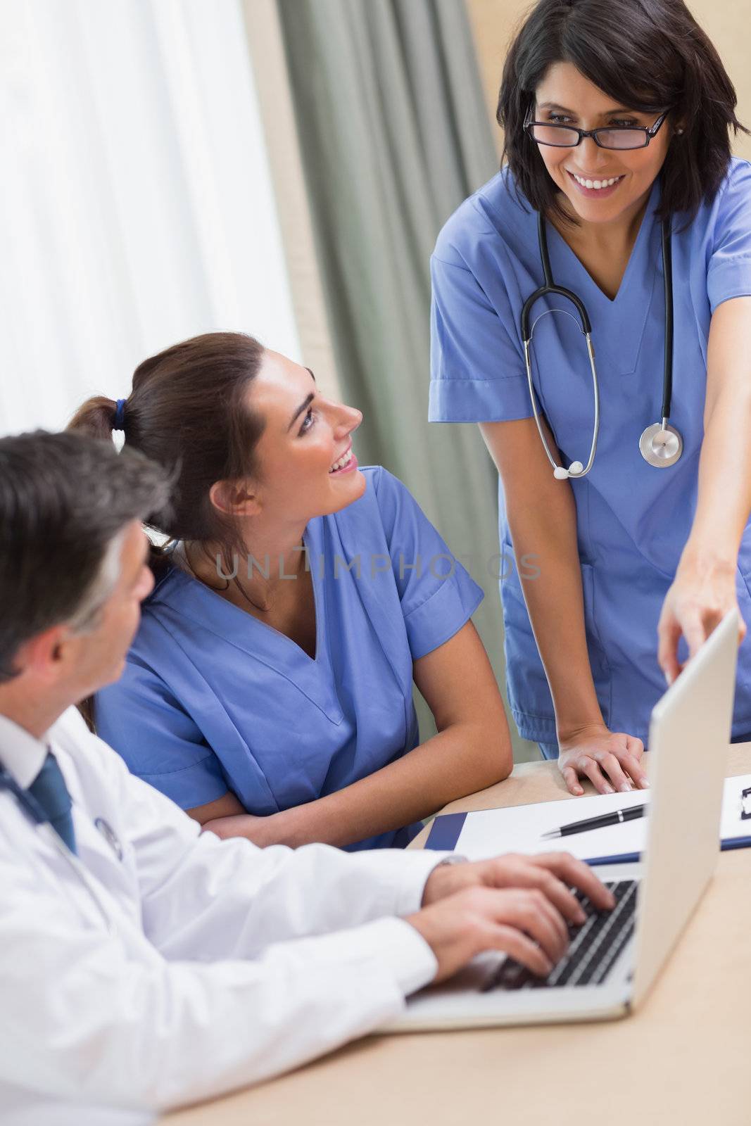Nurse pointing to something on laptop in meeting with doctor and other nurse