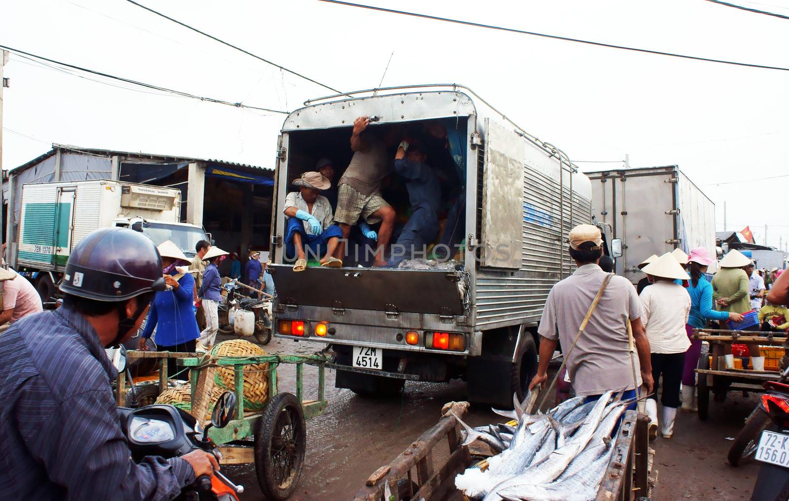 many vehicles as trucks, motorbikes, tricycles, rickshaws go into fishing market make trafiic jam, crowded atmosphere at market in morning. July 15, 2013