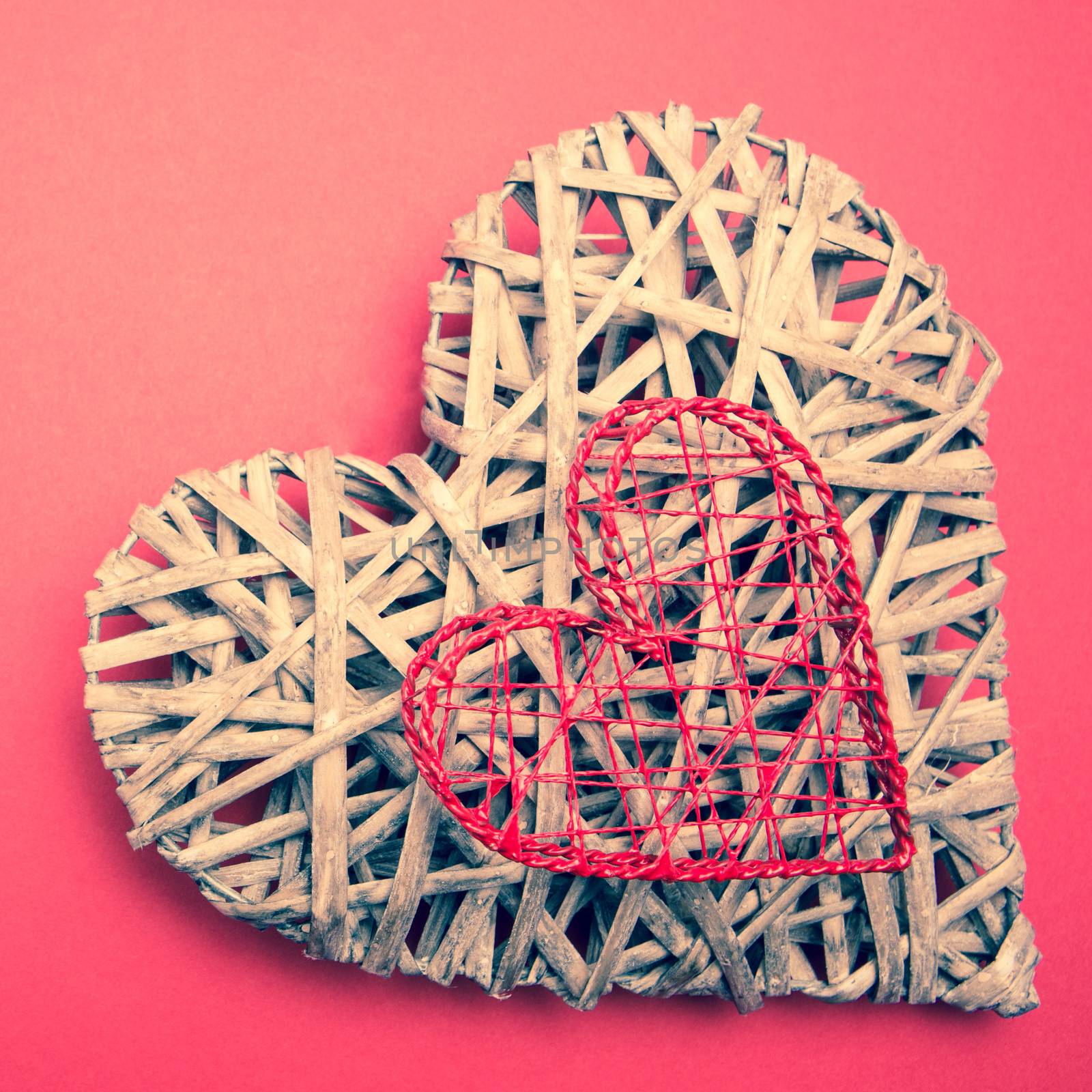 Wicker heart ornament with heart shaped box on pink background