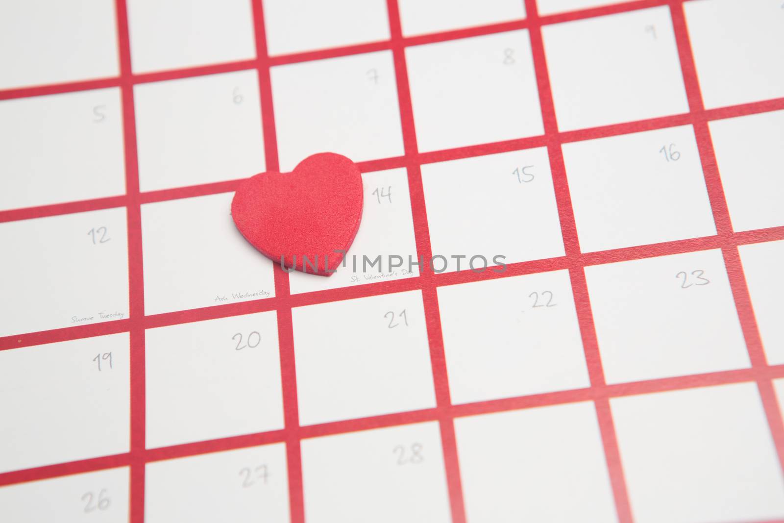 Pink heart resting on valentines day on white and pink calendar