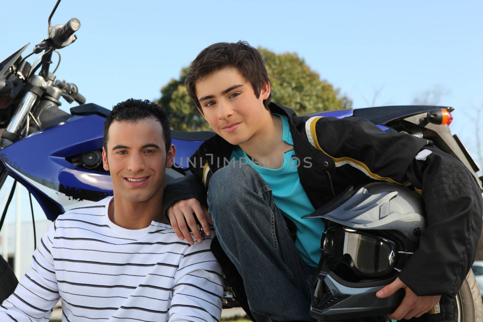 Father and son stood by motorbike by phovoir