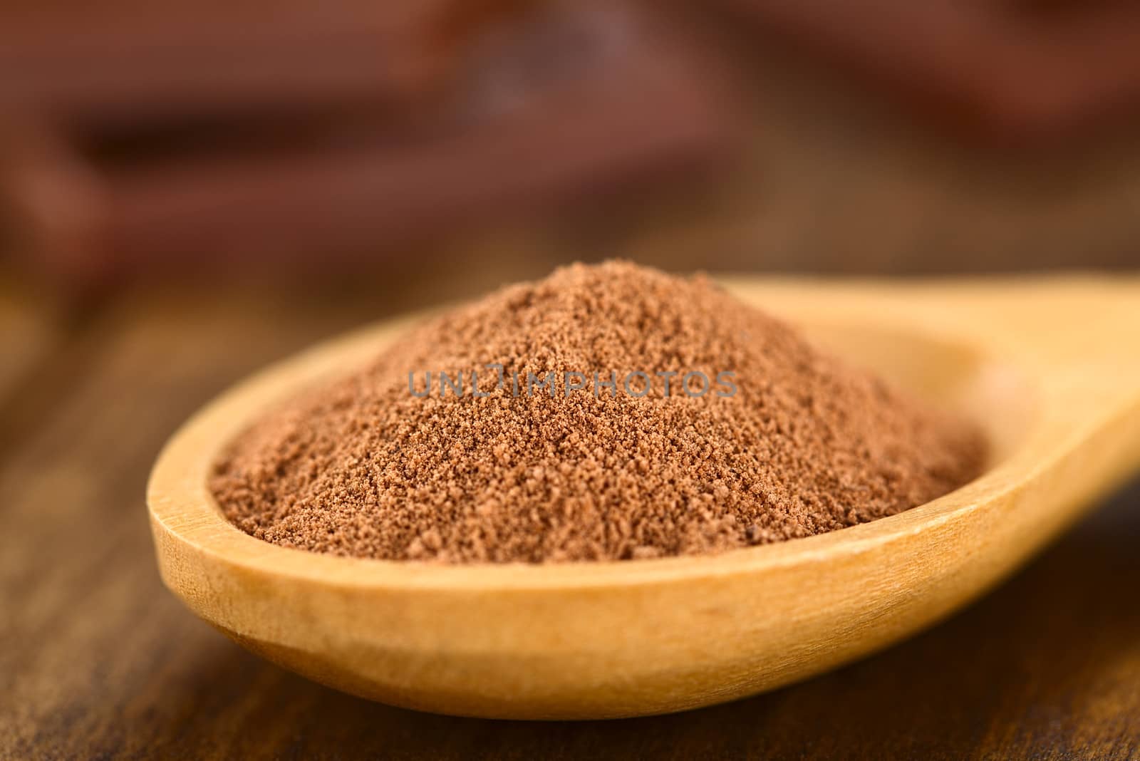 Cocoa powder on wooden spoon with chocolate pieces in the back (Very Shallow Depth of Field, Focus one third into the cocoa)