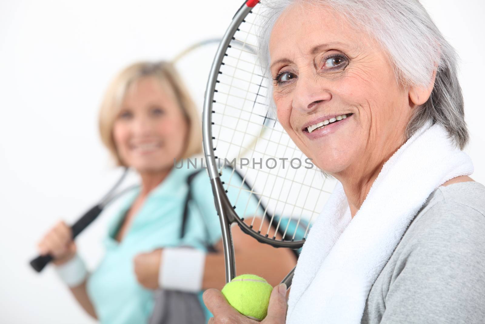 senior women playing tennis by phovoir