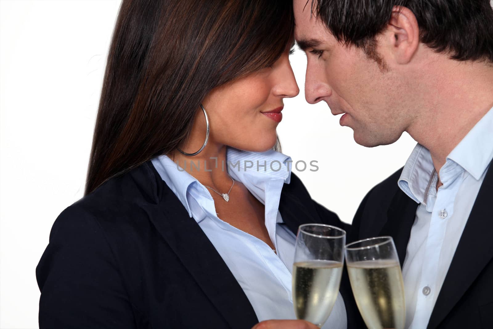 Flirtatious business couple drinking champagne by phovoir