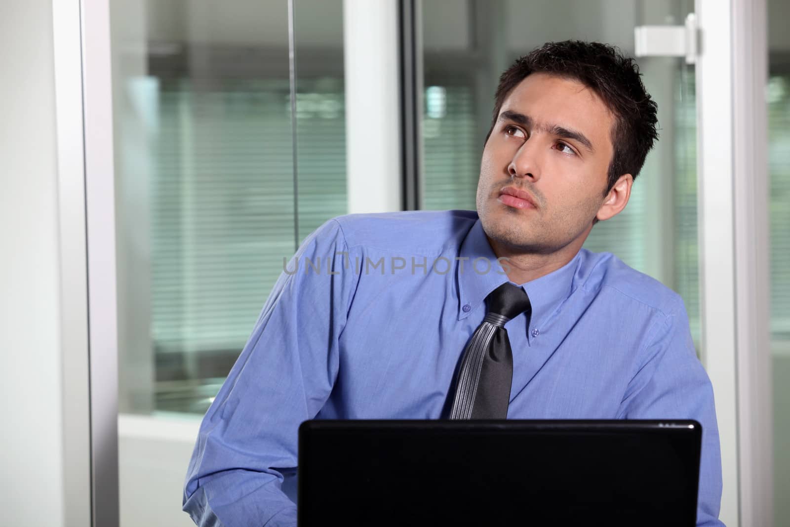 Pensive businessman sat at his desk by phovoir