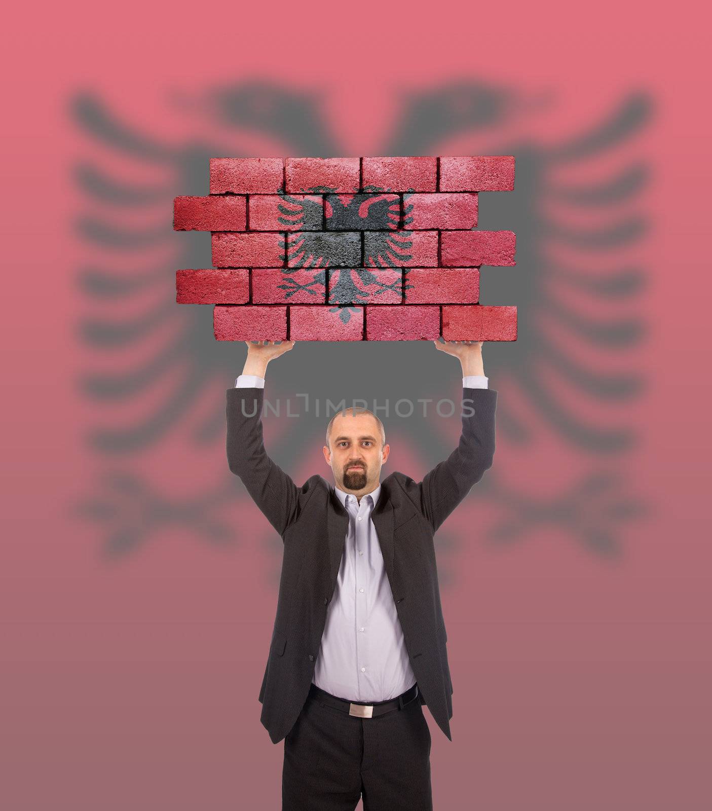 Businessman holding a large piece of a brick wall by michaklootwijk