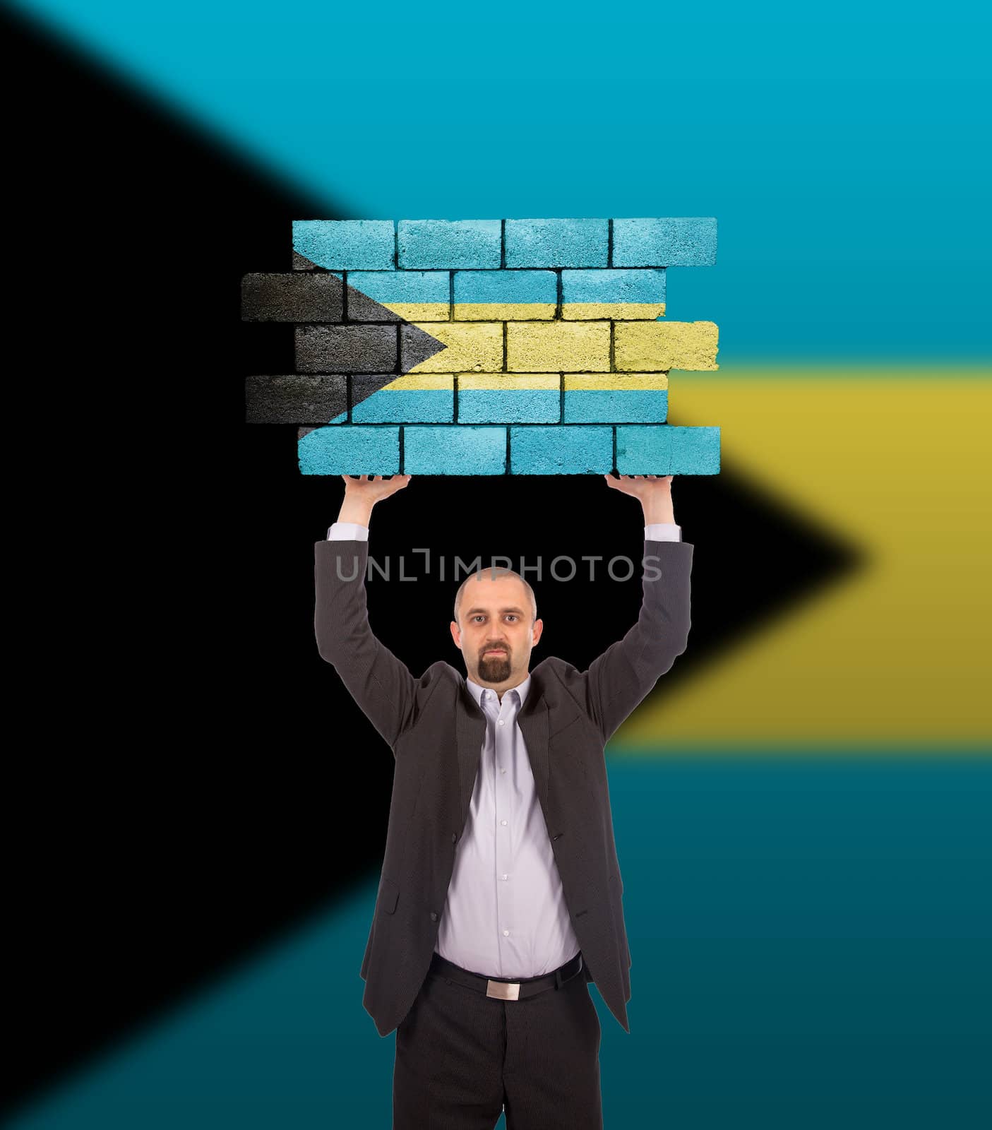 Businessman holding a large piece of a brick wall, flag of the Bahamas, isolated on national flag