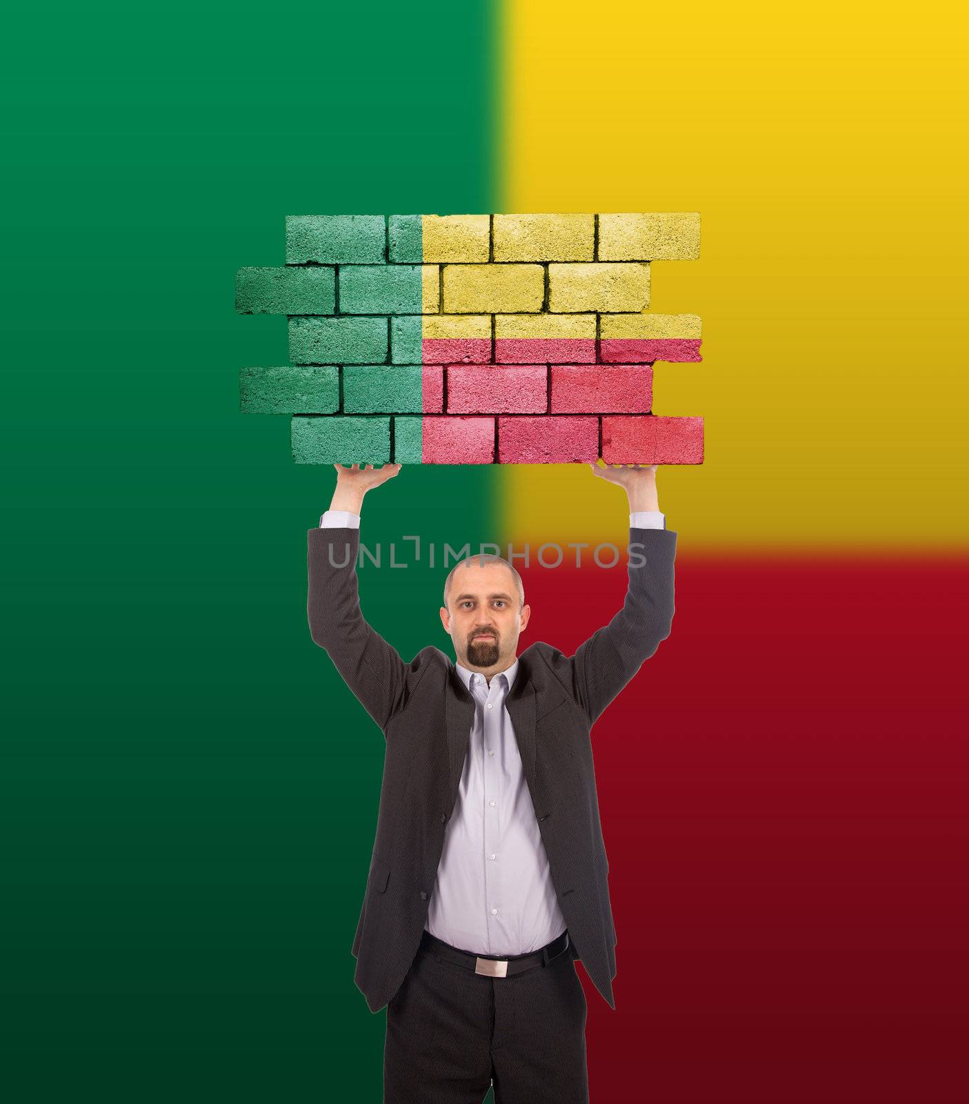Businessman holding a large piece of a brick wall, flag of Benin, isolated on national flag