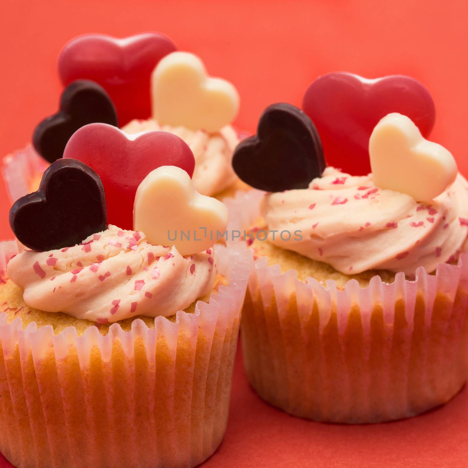 Close up of three valentines cupcakes on red background
