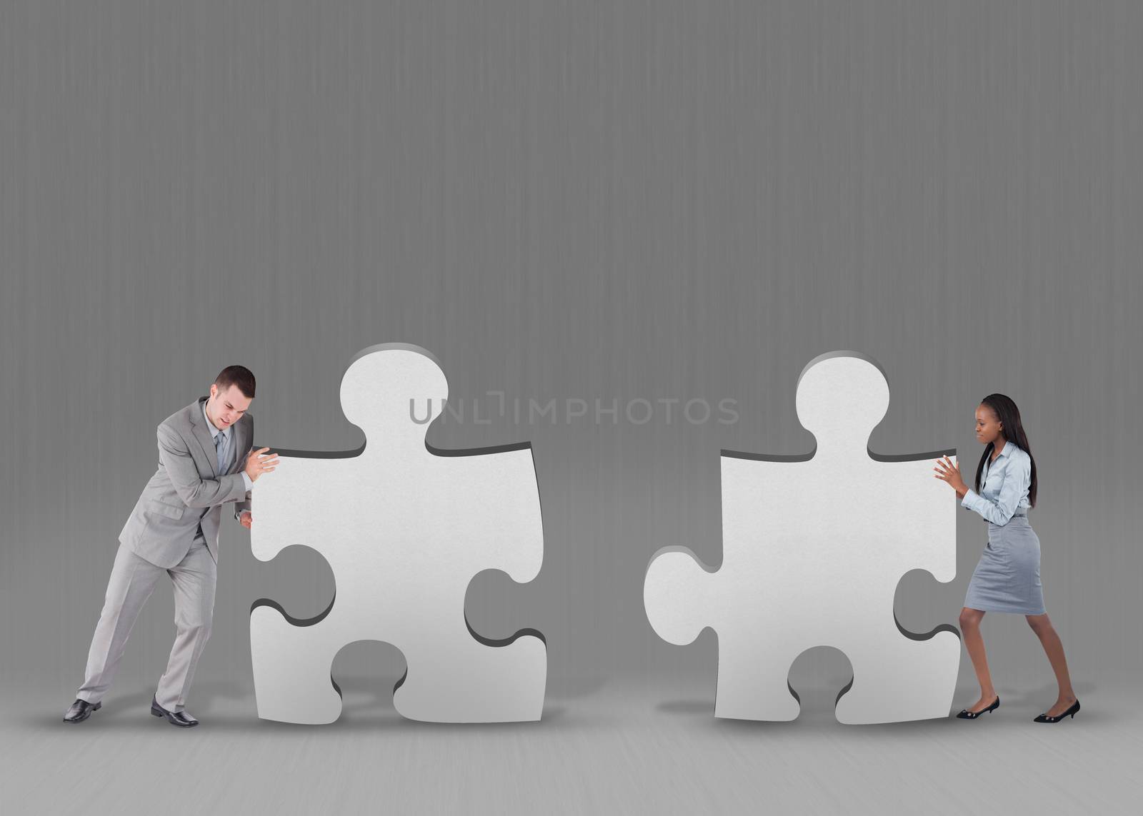 Business people pushing two jigsaw pieces together on grey background