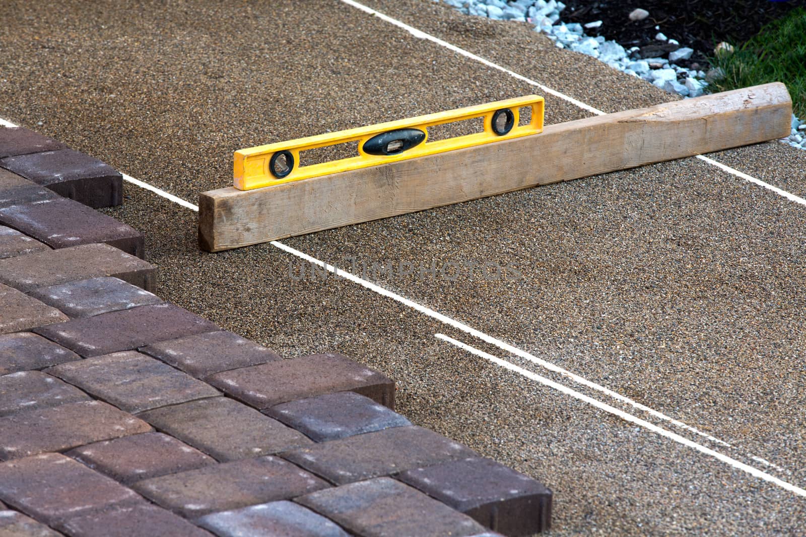 Paving job gets done preciously leveling the sand with yellow level and piece of wood