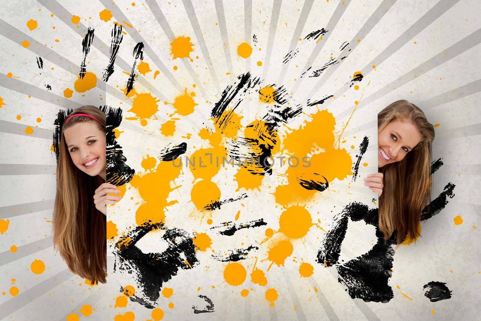 Two pretty girls holding abstract art of yellow ink and black handprints