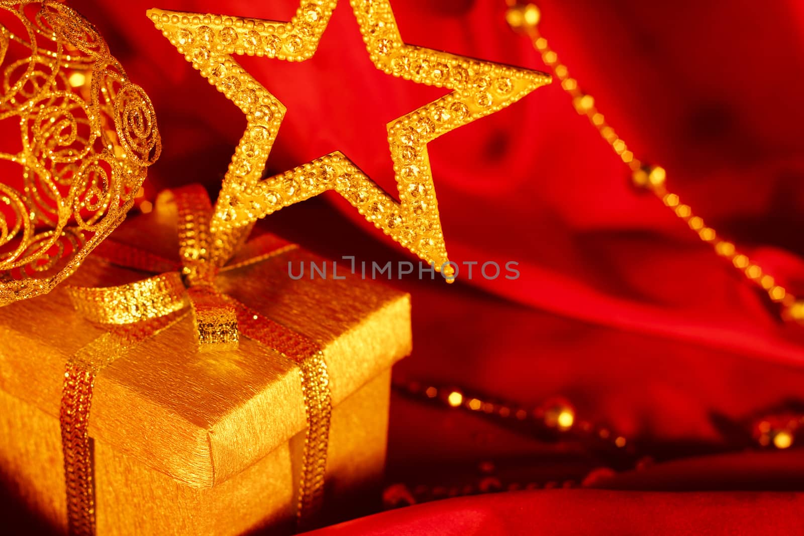 Golden christmas decoration and gift on red fabric background