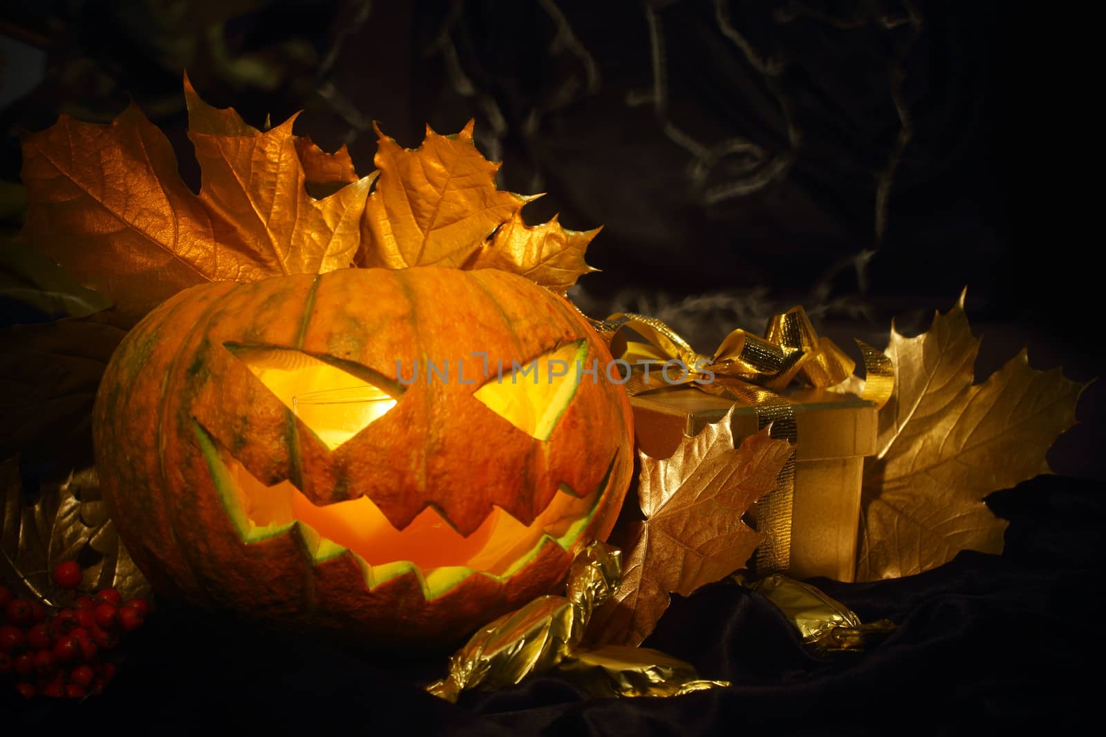 Halloween pumpkin with autumn leafs and gift on black