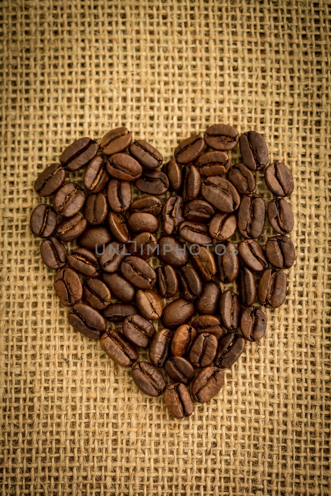 Heart made from roasted coffee beans on burlap sack
