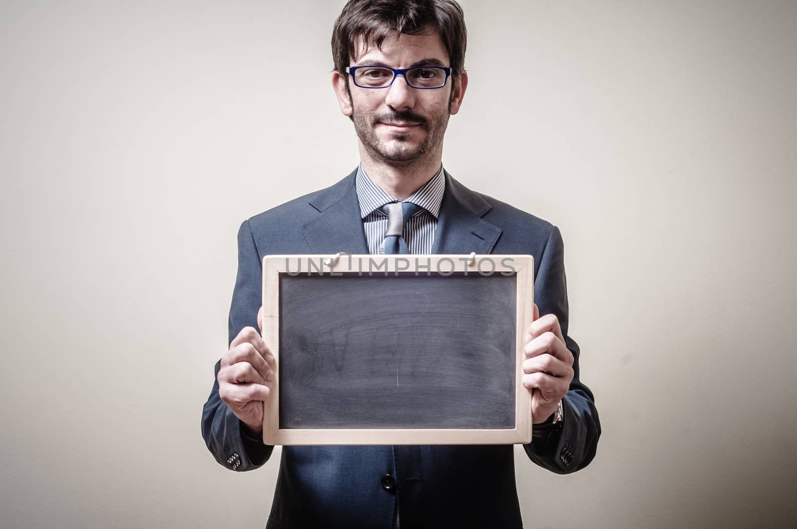 businessman holding blackboard on gray background