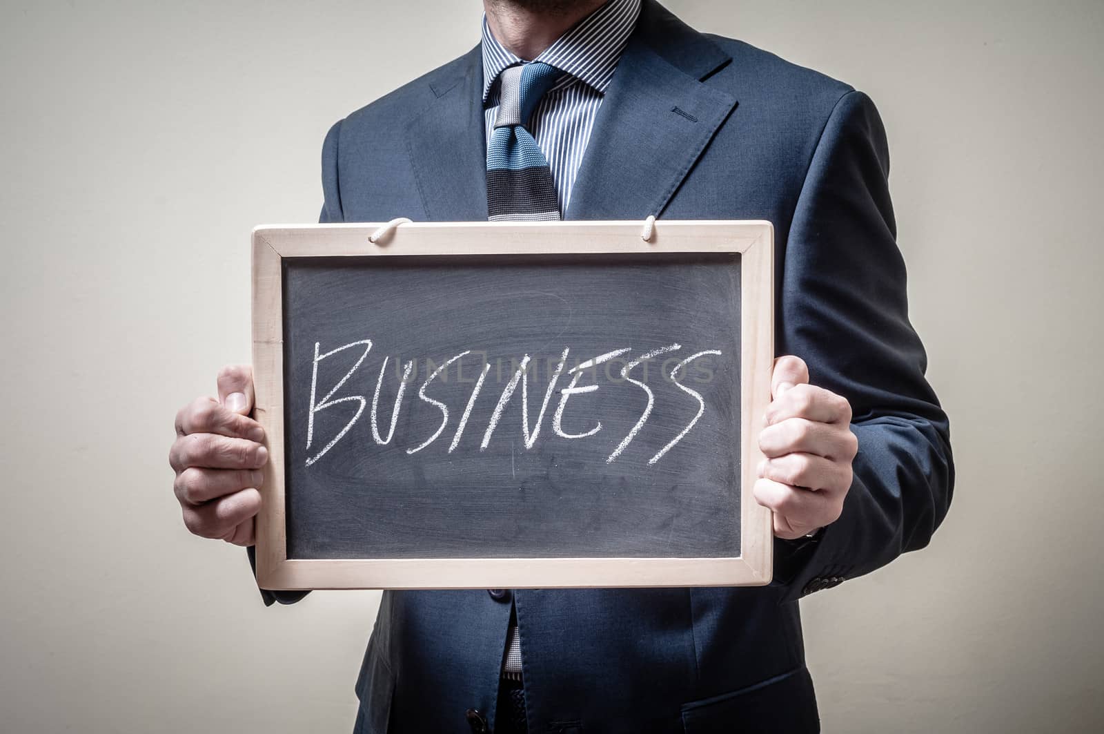 businessman holding blackboard written business on gray background