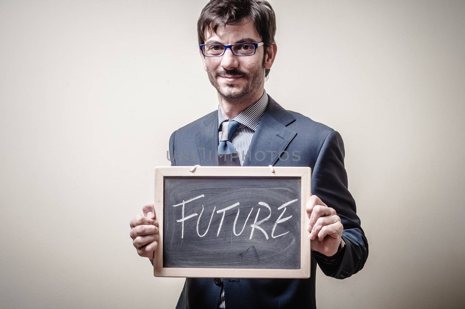 businessman holding blackboard written future on gray background