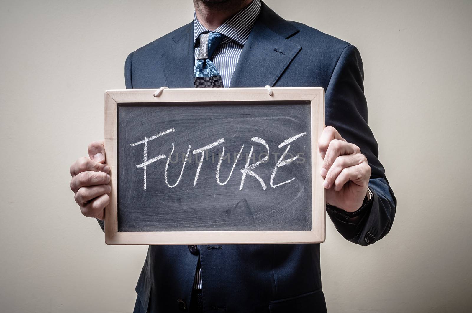 businessman holding blackboard written future on gray background
