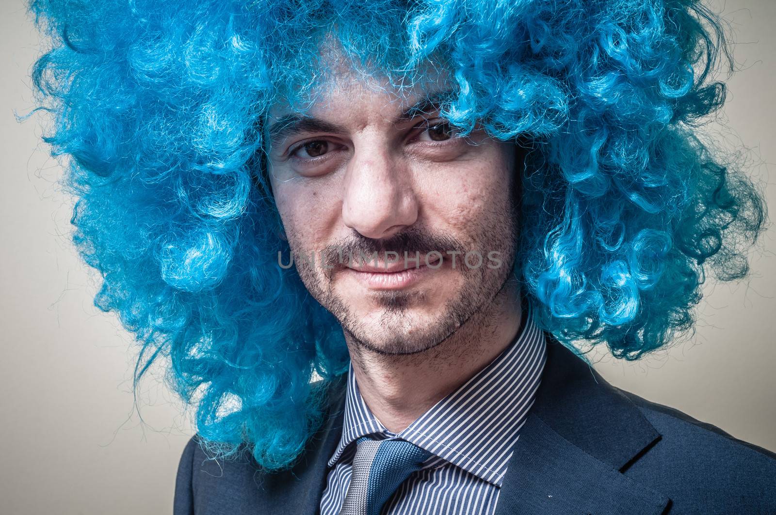 funny businessman with blue wig on  gray background
