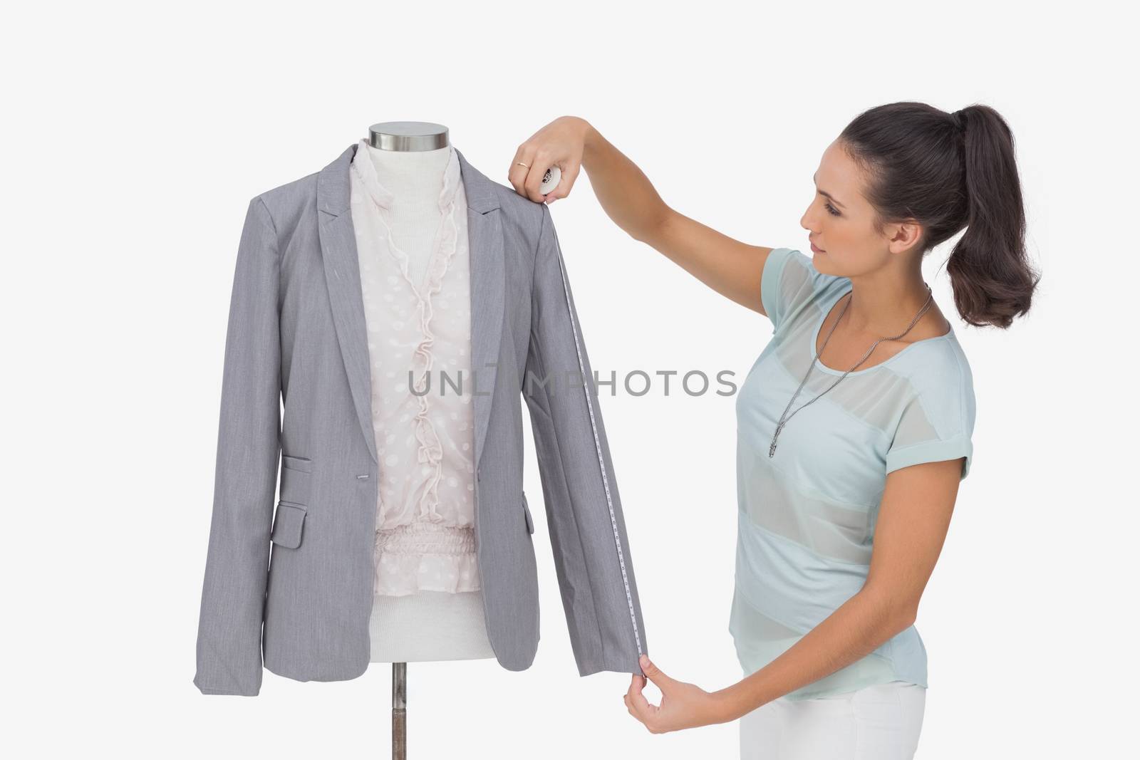 Fashion designer measuring blazer sleeve on white background