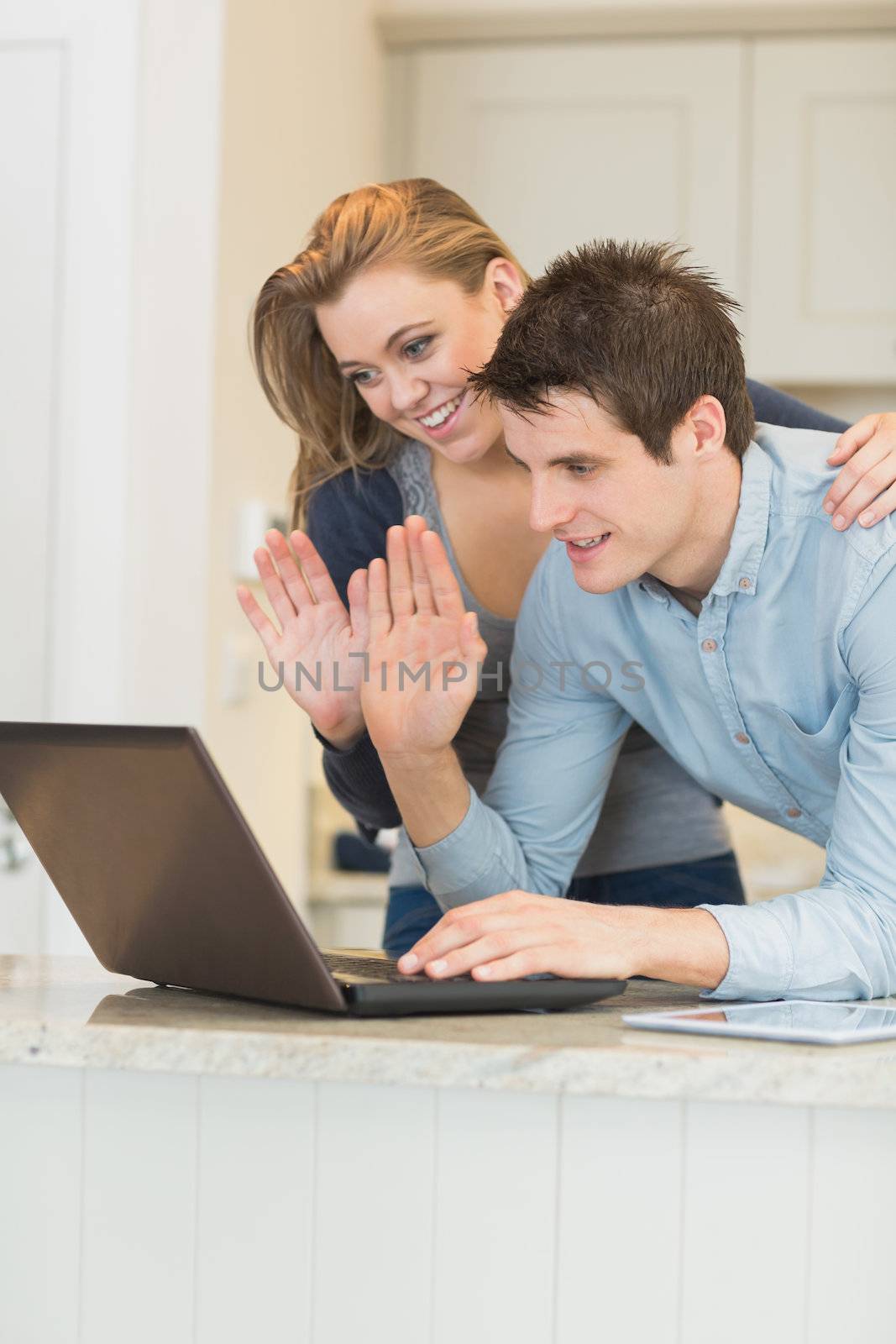 Man and woman use the webcam and wave their hands