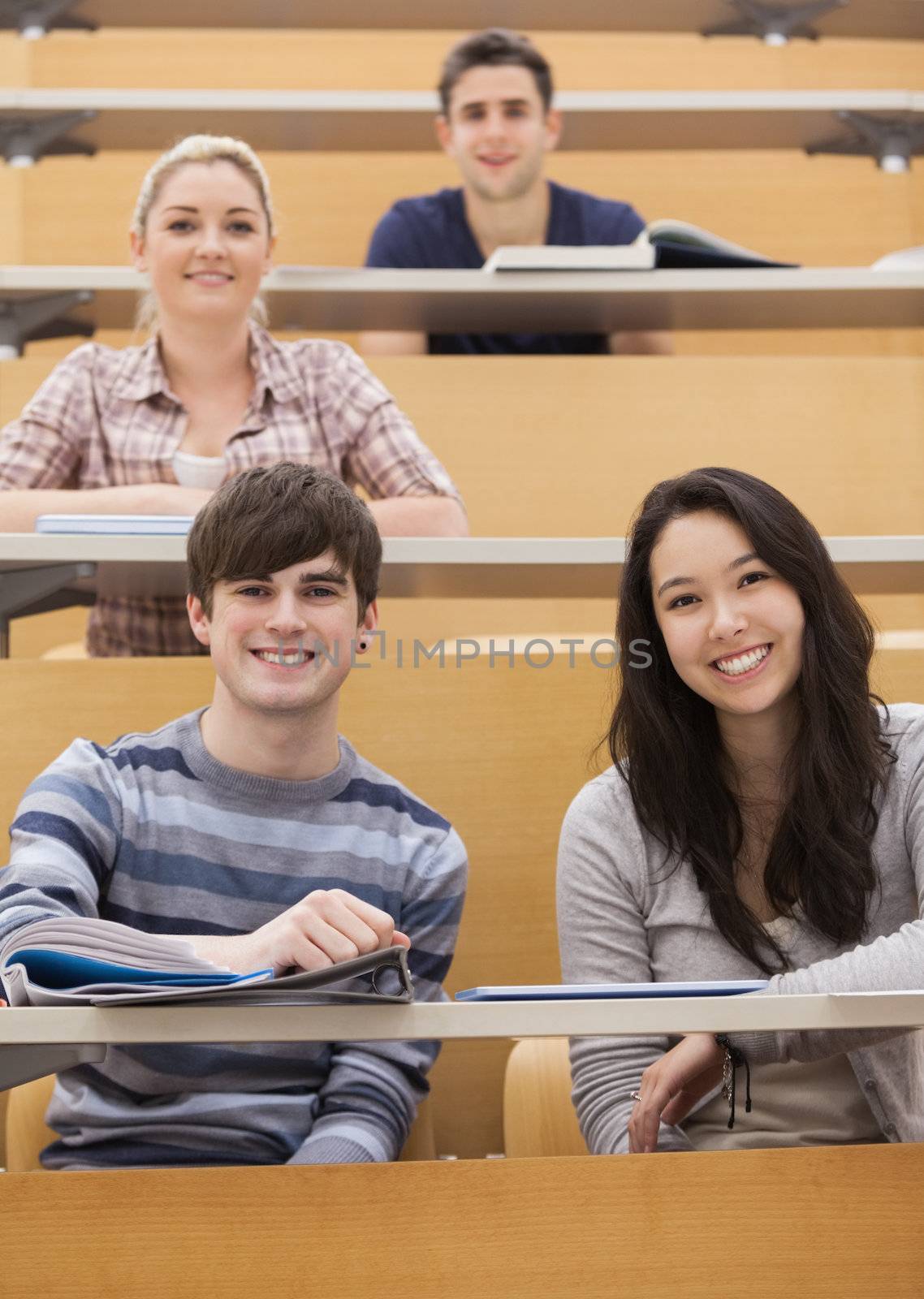 Happy students sitting in a lecture hall by Wavebreakmedia